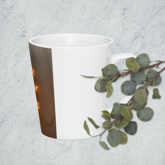 Pocoline handmade latte mug with white and brown design placed next to green eucalyptus leaves
